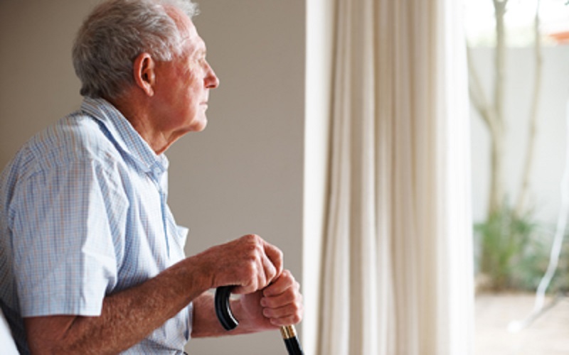 elderly man with a walking stick looking outside