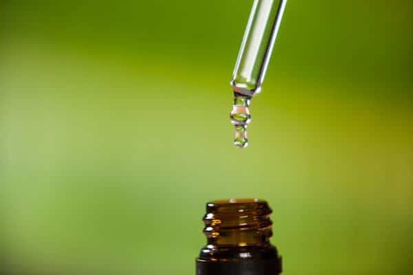 drop oil dripping from pipette into bottle essential oil e1639589609475