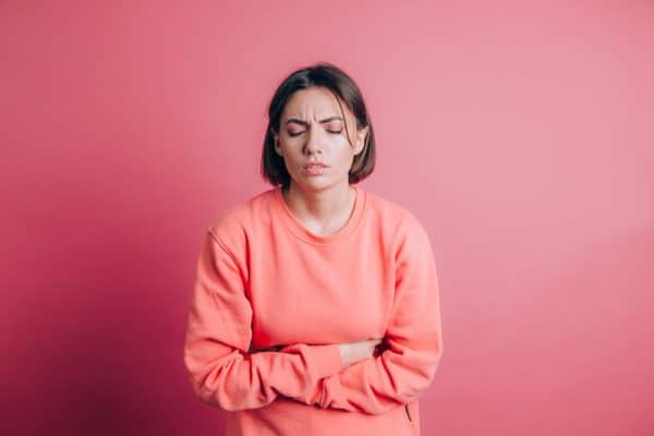 woman wearing casual sweater background suffering stomach ache with painful grimace feeling sudden period cramps gynecology concept e1642593117466