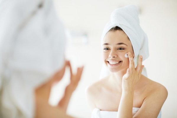 woman putting on face cream e1679490936745